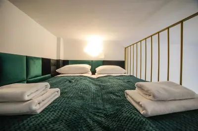 a large bed with a green blanket and pillows on it at CracWoW Saint Sebastian Apartments in Kraków