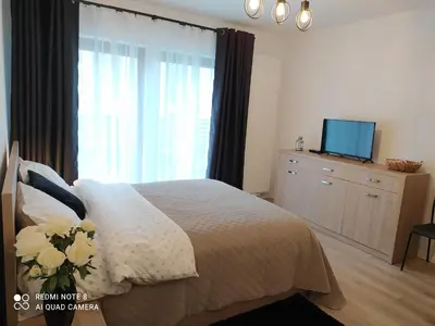 a bedroom with a bed and a chair and a kitchen at Doskonałe mieszkanie z tarasem blisko centrum Krakowa in Kraków