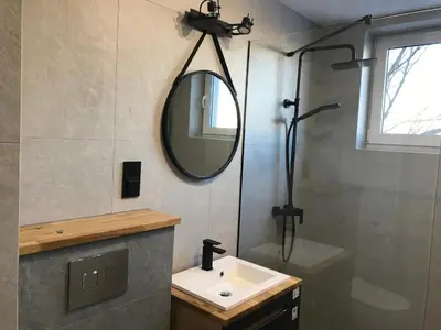 a bathroom with a sink and a mirror and a shower at Pszczelna Loft in Kraków