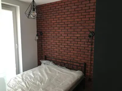 a bedroom with a brick wall and a bed at Pszczelna Loft in Kraków