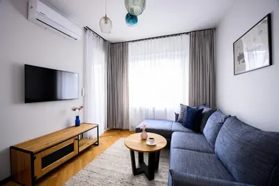 a living room with a blue couch and a table at Native Apartments Barska 69 in Kraków