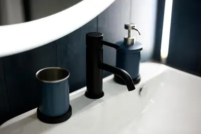 a bathroom sink with a faucet and a cup at Native Apartments Barska 69 in Kraków