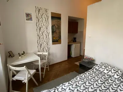 a bedroom with a bed and a desk and a kitchen at Historic Apartment in Kraków