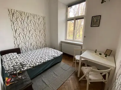 a bedroom with a bed and a desk and a window at Historic Apartment in Kraków