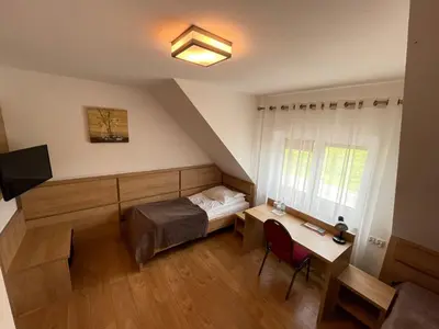 a bedroom with a bed and a desk and a window at Hotel August in Brzesko