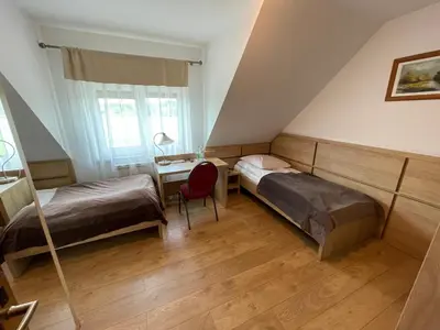 a bedroom with two beds and a desk with a chair at Hotel August in Brzesko