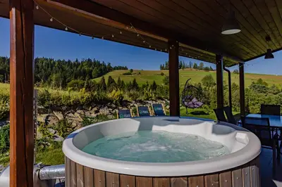 a jacuzzi tub on a deck with a view at Maciejowe Wzgórze Domek z dwoma niezależnymi apartamentami ze SPA - Sauna, Jacuzzi, Tężnia, Izba Solna i Solankowa, Balia na wyłączność z hydromasażami in Rabka