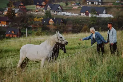 two people standing in a field with a horse at Maciejowe Wzgórze Domek z dwoma niezależnymi apartamentami ze SPA - Sauna, Jacuzzi, Tężnia, Izba Solna i Solankowa, Balia na wyłączność z hydromasażami in Rabka