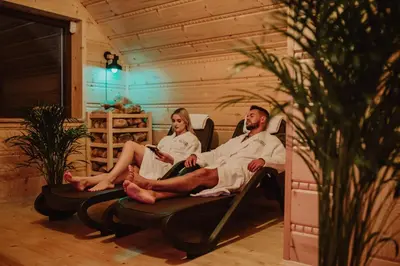 a man and woman sitting on a couch at Maciejowe Wzgórze Domek z dwoma niezależnymi apartamentami ze SPA - Sauna, Jacuzzi, Tężnia, Izba Solna i Solankowa, Balia na wyłączność z hydromasażami in Rabka