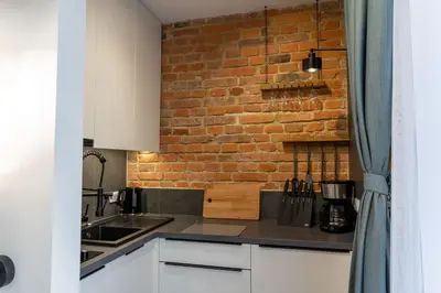 a kitchen with white cabinets and a brick wall at mN apartments home - Wieliczka Town in Wieliczka