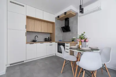 a kitchen with white cabinets and a table and chairs at Lux Apartment Grzegórzecka Estate Cracow by Renters Prestige in Kraków