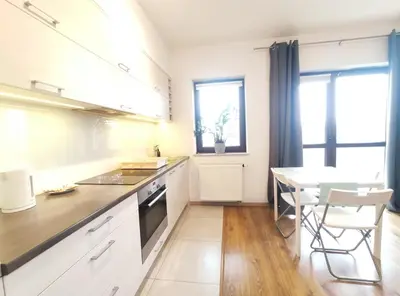 a kitchen with white cabinets and a table with chairs at Śliczna 34A by Homeprime in Kraków