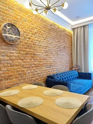 a dining room with a table and a brick wall at TRUE COLORS Old Town Apartments - Wawel & Vistula River - Homelike Kraków in Kraków