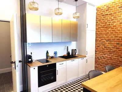 a kitchen with white cabinets and a brick wall at TRUE COLORS Old Town Apartments - Wawel & Vistula River - Homelike Kraków in Kraków