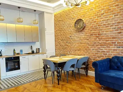 a kitchen with a table and a brick wall at TRUE COLORS Old Town Apartments - Wawel & Vistula River - Homelike Kraków in Kraków