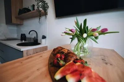 a wooden table with a plate of fruit and a vase of flowers at ZatoRest 43 by Housine in Zator