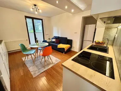 a kitchen and living room with a table and chairs at Mała Góra Apartment in Kraków