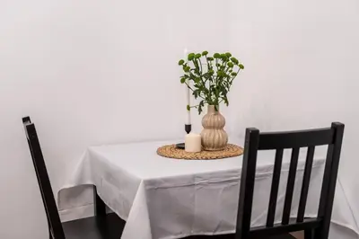 a white table with a vase with flowers in it at St. Miasto Studio Kraków in Kraków