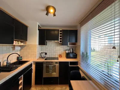 a kitchen with black cabinets and a sink and a window at Apartament Sołtysowska- garaż bezpłatny, NEAR Tauron Arena, EXPO in Kraków