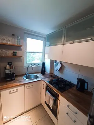 a kitchen with a sink and a stove and a window at Apartament boBoski in Wadowice
