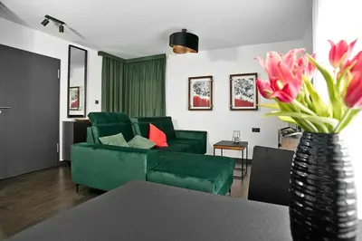 a living room with a green couch and a vase with flowers at Near Sanktuarium Beautiful View and Free Parking in Kraków