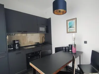 a kitchen with black cabinets and a table with chairs at Near Sanktuarium Beautiful View and Free Parking in Kraków