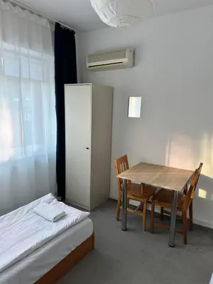 a room with a table and a bed and a table and chairs at Hostel Demi in Kraków