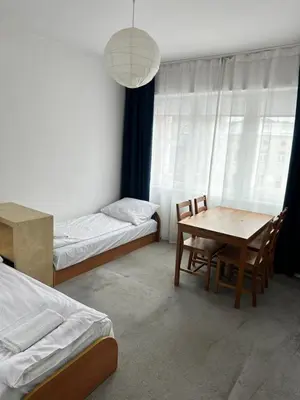 a room with two beds and a table and chairs at Hostel Demi in Kraków