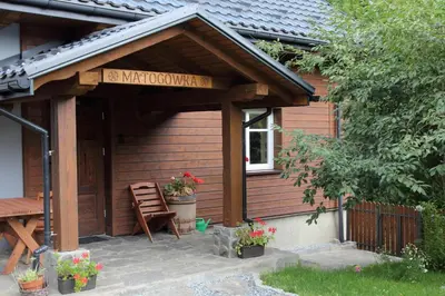 a wooden building with a porch with a bench and flowers at MATOGÓWKA in Krzeszowice