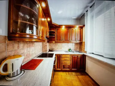 a kitchen with wooden cabinets and a sink at Krupnicza Apartment in Kraków