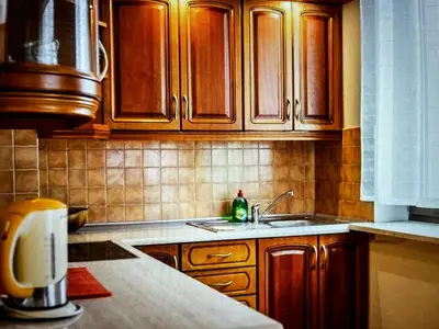 a kitchen with wooden cabinets and a sink at Krupnicza Apartment in Kraków