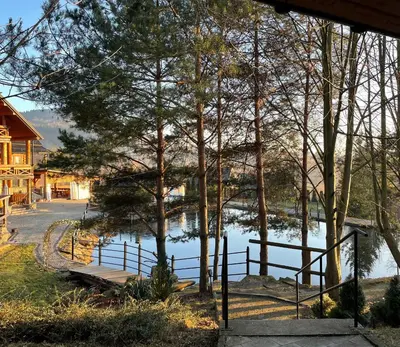 a view of a lake with a bridge and trees at Domek Nad Stawem II in Limanowa