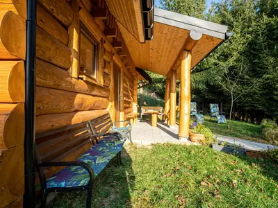 a bench sitting outside of a wooden building at Domek Nad Stawem II in Limanowa