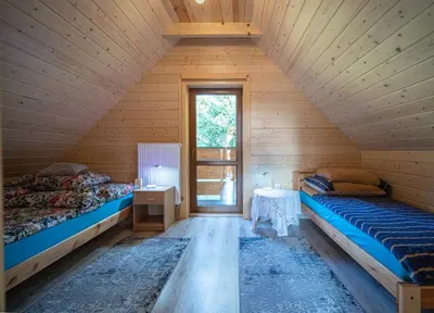 a attic room with two beds and a window at Domek Nad Stawem II in Limanowa
