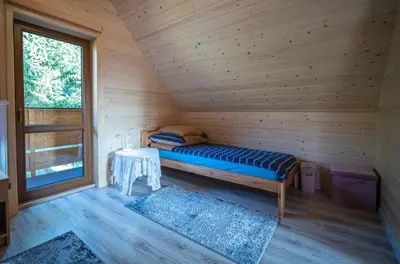 a bed in a wooden room with a table at Domek Nad Stawem II in Limanowa