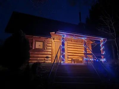 a log cabin with christmas lights on the stairs at Domek Nad Stawem II in Limanowa