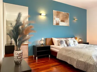 a bedroom with a bed and a blue wall at Angel MINT Apartment - FREE PARKING - Balcony in Kraków
