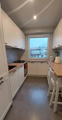 a kitchen with white cabinets and a large window at Przytulne mieszkanie w Olkuszu/ Cosy apartment in Olkusz in Olkusz