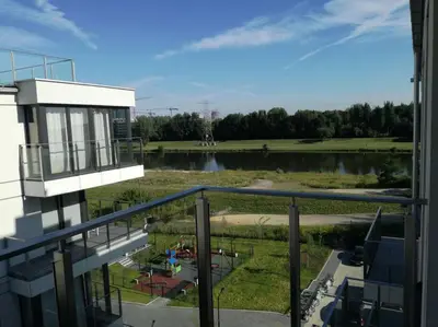 a kitchen with a wooden table and white cabinets at White and Bright Riverside View Flat with Parking, Bike Access, and Onsite Gym in Kraków