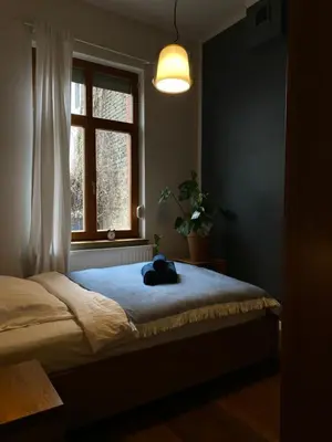 a bedroom with a bed with a blue blanket and a window at D7 Apartment in Kraków