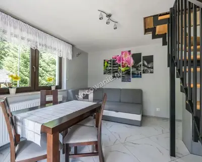 a dining room with a table and chairs and a couch at Domki Letniskowe SOBALSKI in Zawoja
