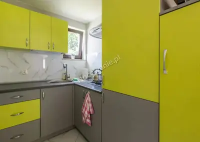 a kitchen with green and yellow cabinets and a sink at Domki Letniskowe SOBALSKI in Zawoja