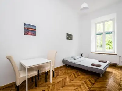 a room with a bed and a table and chairs at Szczebel in Kraków
