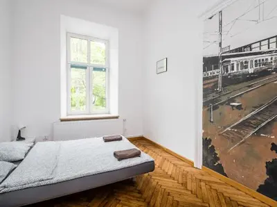 a white room with a bed and a painting on the wall at Szczebel in Kraków
