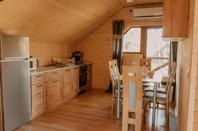 a kitchen with a refrigerator and a table with chairs at Apartament Sosnowy Domek Piętro Zator Graboszyce in Graboszyce