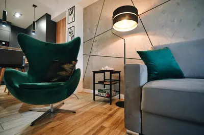 a cat sitting in a green chair next to a couch at ApartHome 25 by Housine in Zator