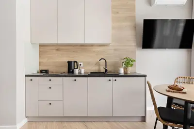 a kitchen with white cabinets and a table at Artis Apartments by Housine in Zator