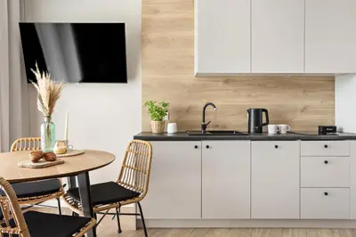 a kitchen with white cabinets and a table at Artis Apartments by Housine in Zator