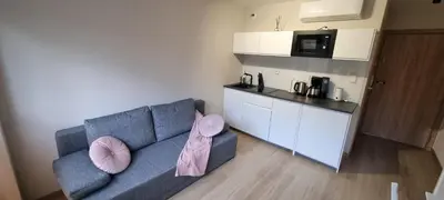 a living room with a blue couch and a kitchen at Apartament Xavier Kraków in Kraków