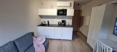 a living room with a couch and a kitchen at Apartament Xavier Kraków in Kraków